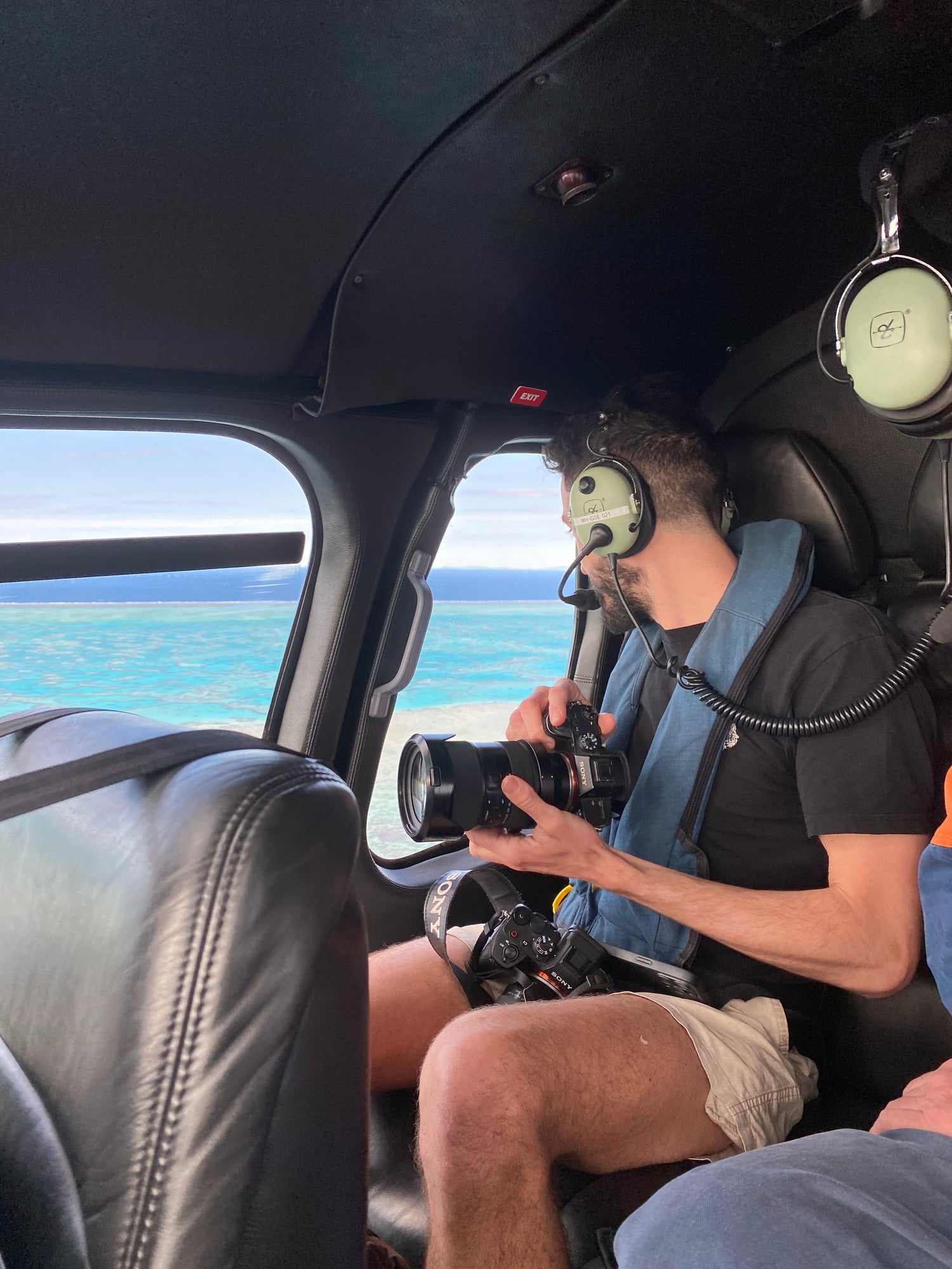 Person inside a helicopter holding a camera with a scenic view outside